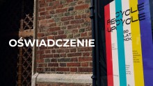 zdjęcie plakatu wystawy Recycle-upcycle w gablocie. W tle ceglana ściana i fragment wrót Centrum św. Jana