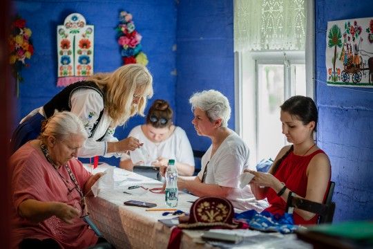 grupa kobiet haftuje w zabytkowej chałupie