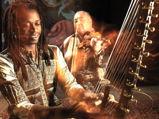 Na pierwszym planie Buba Badje Kujateh grajacy na instrumencie cora, na drugim Stanisław Soyka ze skrzypacami.  TALES Stanisław Soyka & Buba Badje Kujateh. 13. Festiwal Kultur "Okno na świat". Koncert 26 sierpnia 2023