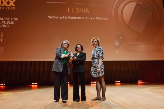zdjęcie 3 kobiet na sxenie, dwie trzymają statuetkę jedna wręczyła nagrodę. W tle napis "LeŚnia"