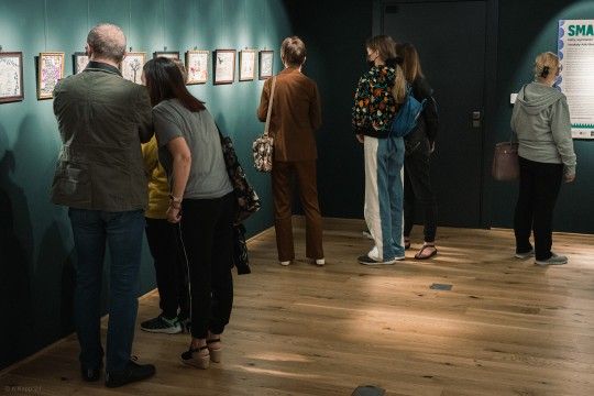 Grupa osób ogląda wystawę w galerii.