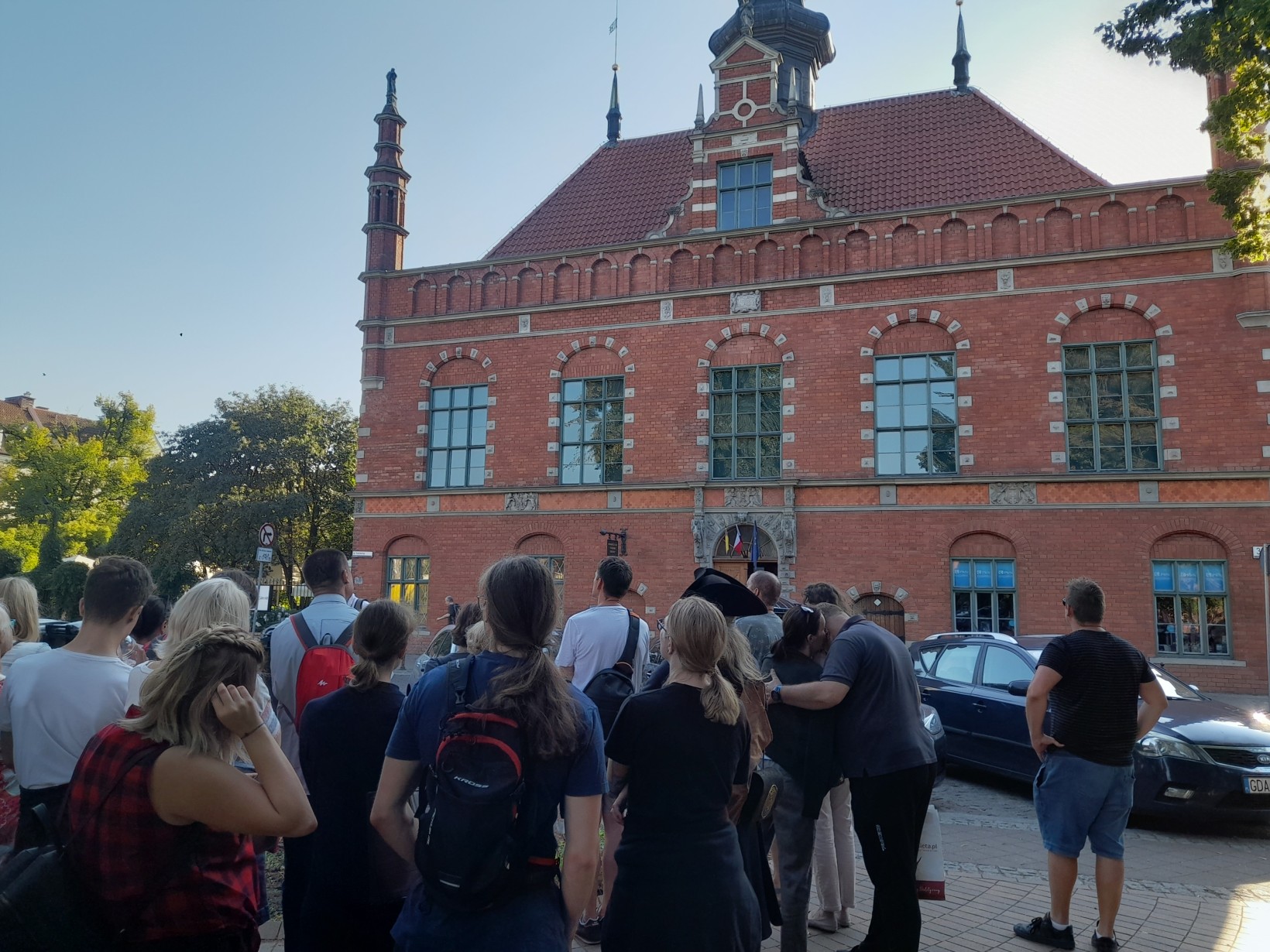 zdjęcie na zewnątrz, ludzie przyglądają się zabytkowemu budynkowi Ratuszowi Saromiejskiemu