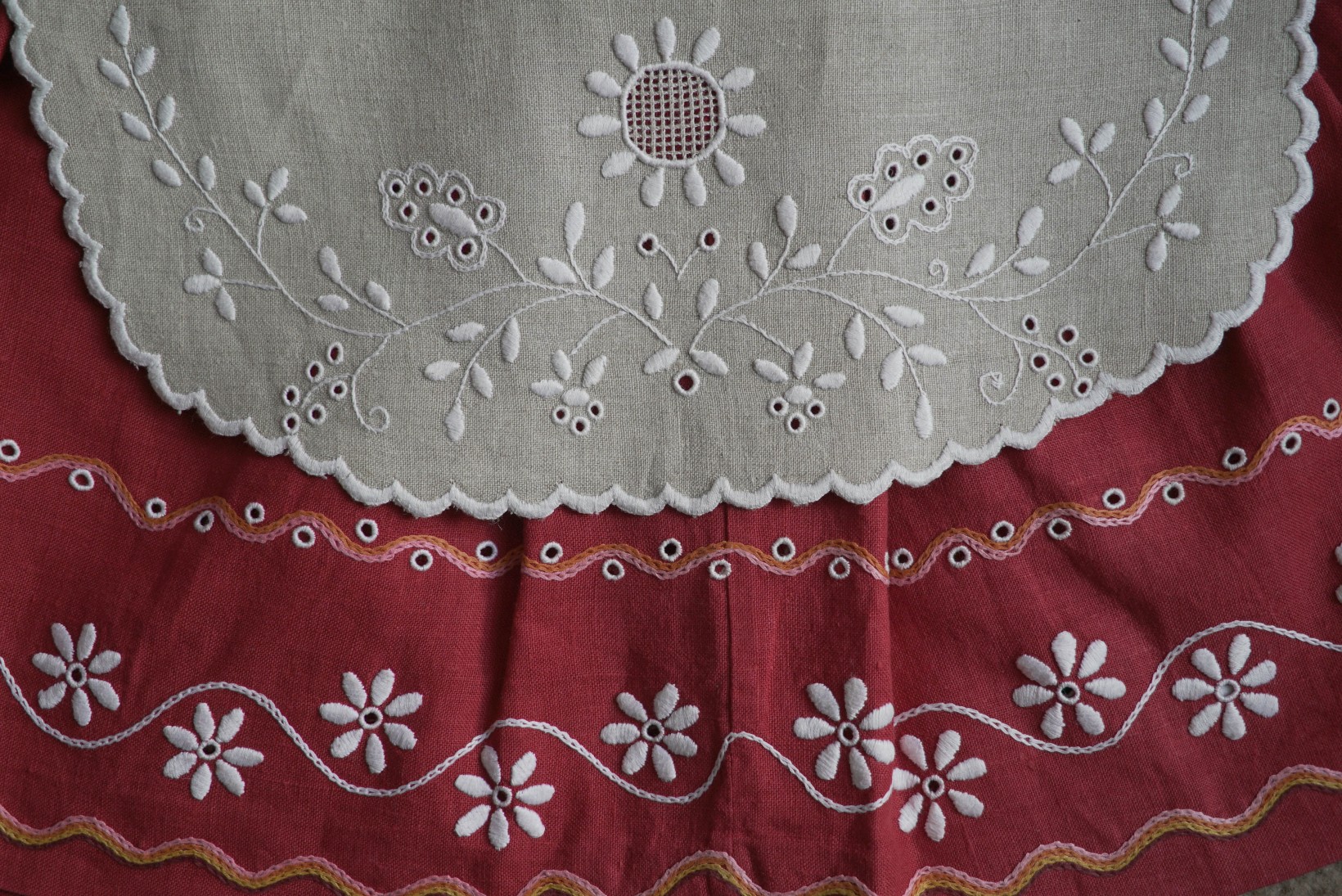 zdjęcie fragmentu stroju powiślańskiego, czerwona spódnica i biały fartuszek z białym haftem