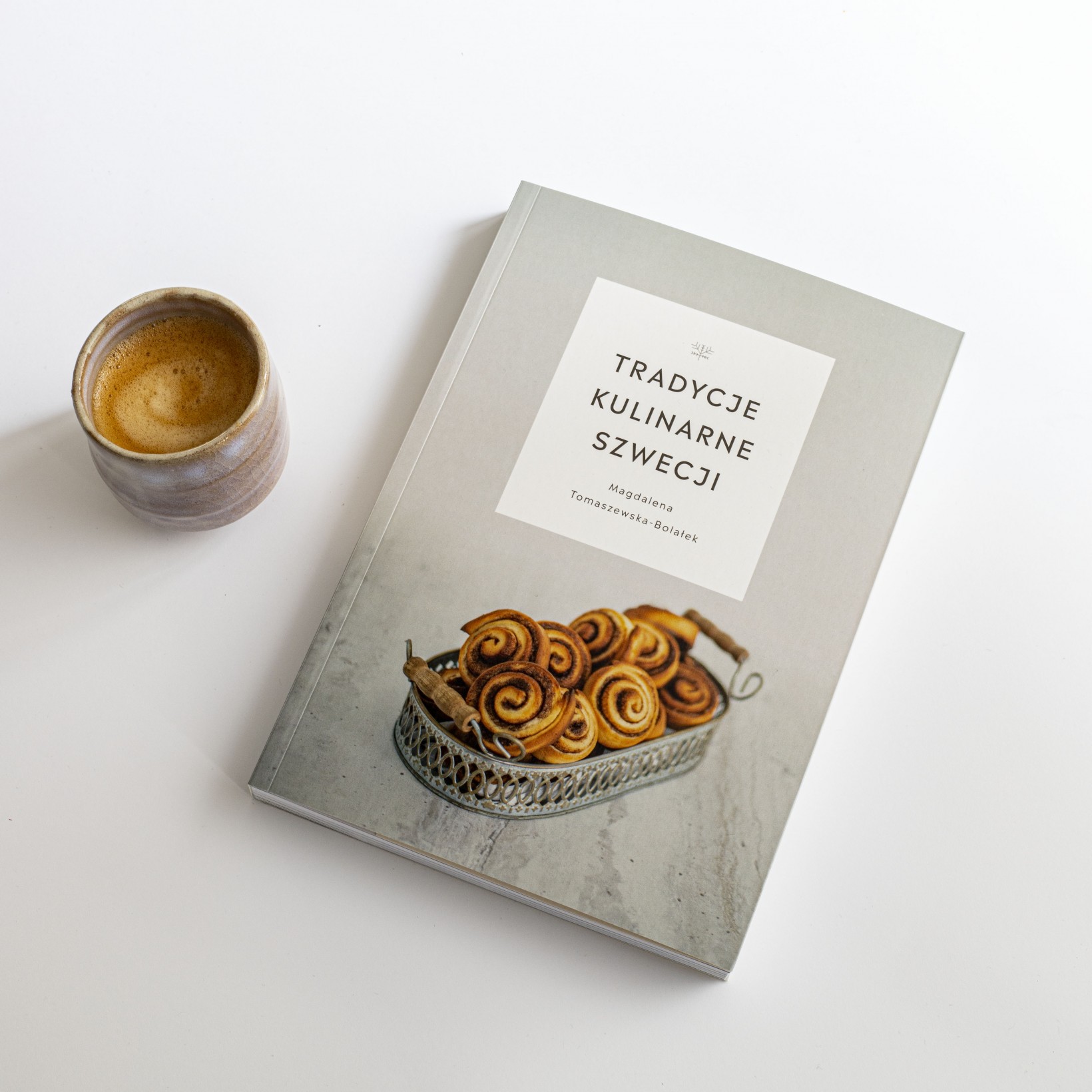 zdjęcie kubka z kawą i książki pt. "Tradycje kulinarne Szwecji"