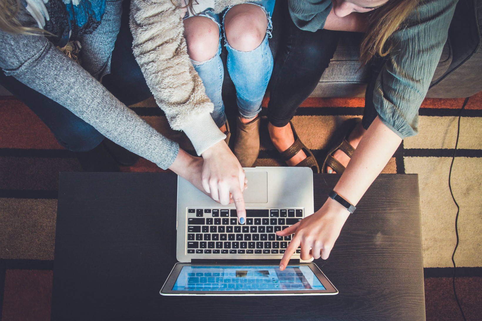 zdjęcie wewnątrz, dłonie wskazują na monitor laptopa, ujęcie z lotu ptaka