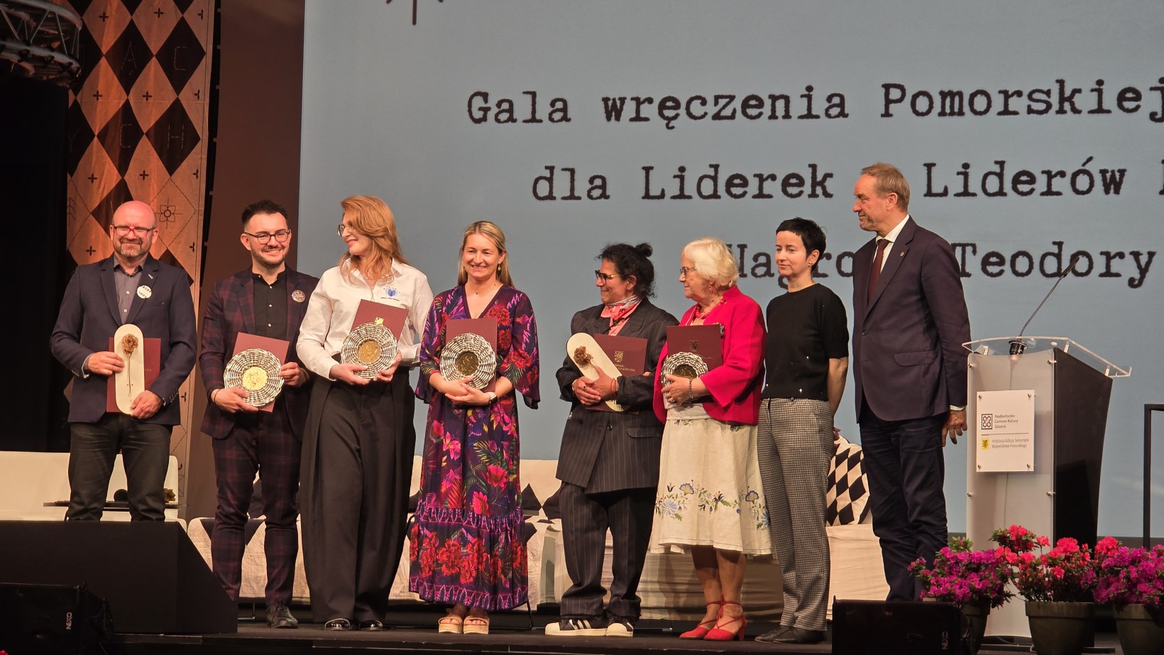 zdjęcie ludzi na scenie, statuetki, kwiaty