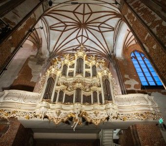 zdjęcie organów w Centrum sw. Jana, biały ozdobny prospekt (obudowa instrumentu) i ceglane, filary gotyckiego zabytku