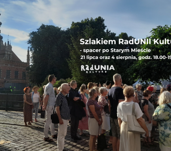 zdjęcie podczas spacaceru, na nim ratusz staromiejski, kilkanaścioro ludzi, napisy z nazwą wydarzenia, godziną, dekoracjami w motywie NCK